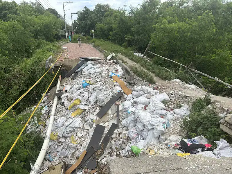 Vista del Puente de Santa Elena colapsado, cubierto por una gran cantidad de escombros y bolsas de desecho que bloquean totalmente el paso.